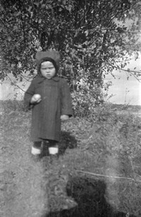 Lata 60. XX wieku. Chłopiec z jabłkiem na tle jabłoni